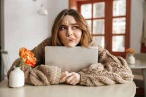 student holding computer looking frustrated